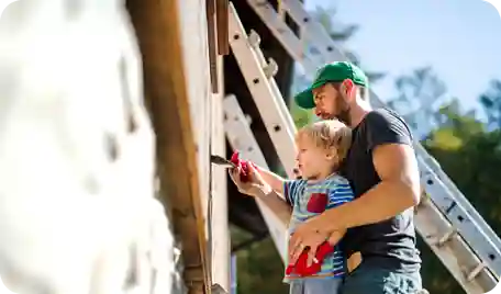 A father with his young child, painting a home
