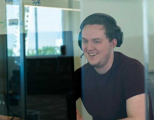 Support rep smiling while answering a phone call on his headset.